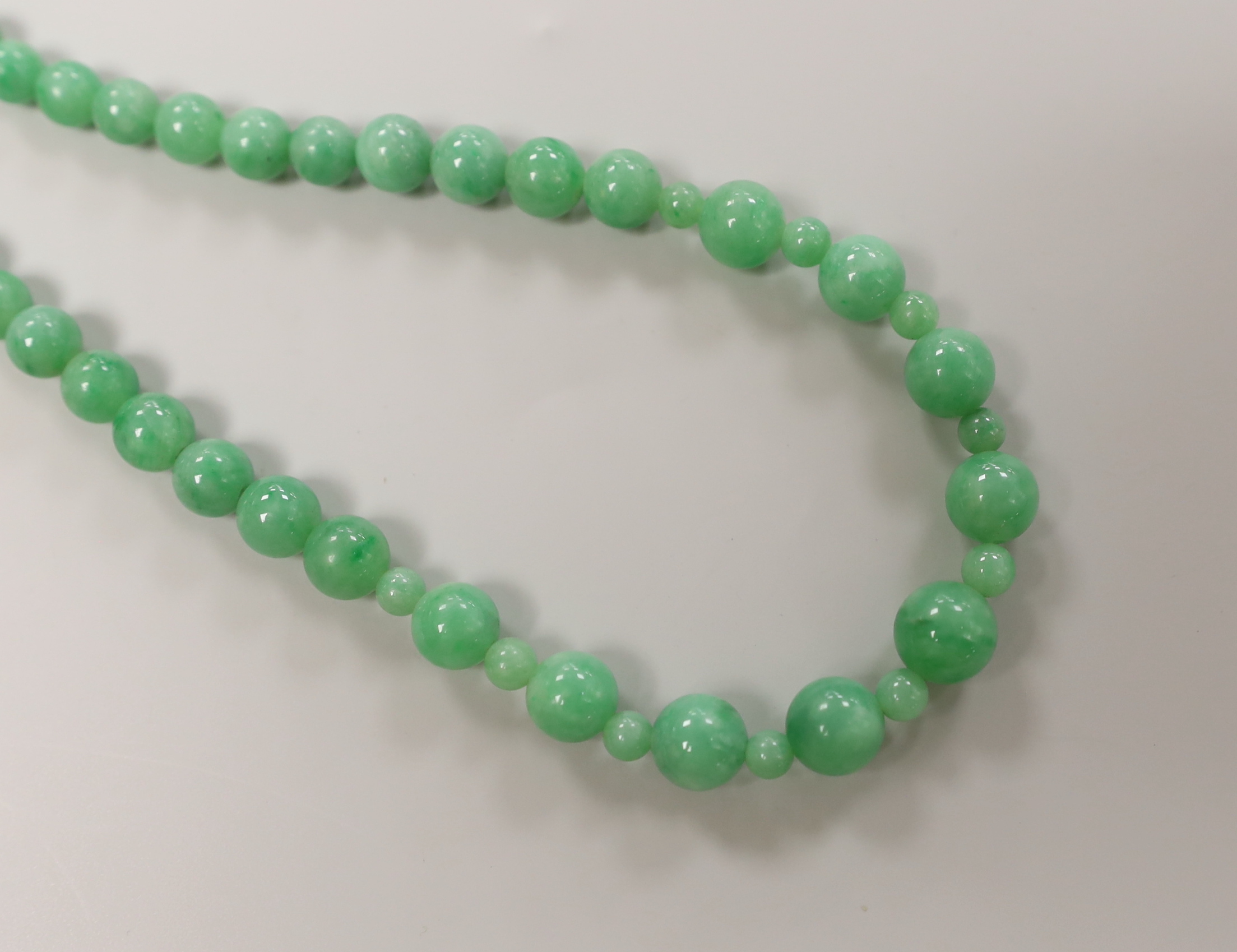 A Chinese jadeite carving and jadeite bead necklace, carving 6.5cm long